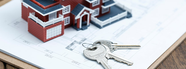 Partnerschaft Ein Modellhaus und Schlüssel liegen auf einem Bauplan.